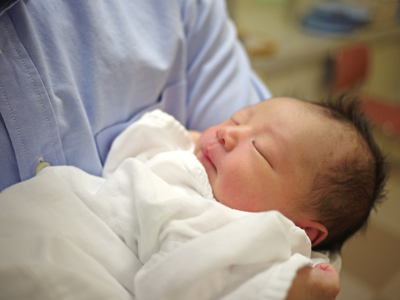 Newborn baby held by father